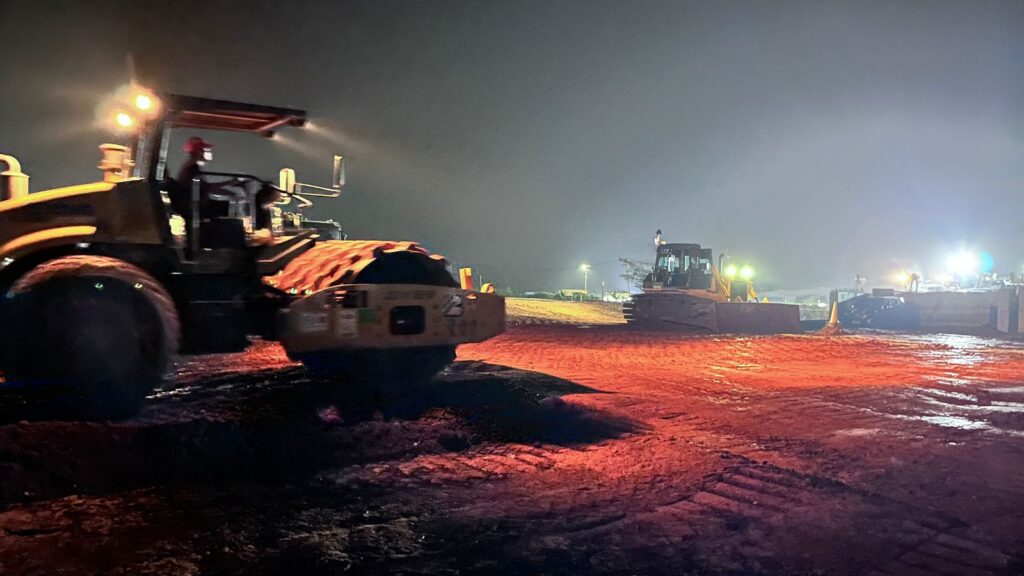 memadatkan dan meratakan tanah basah di lokasi pembangunan Proyek Tol Akses Patimban
